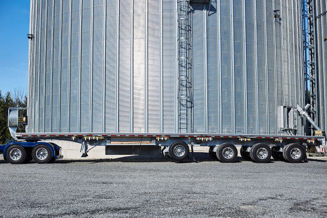 A Flatbed Trailer Parked In Front Of A Grain Silo